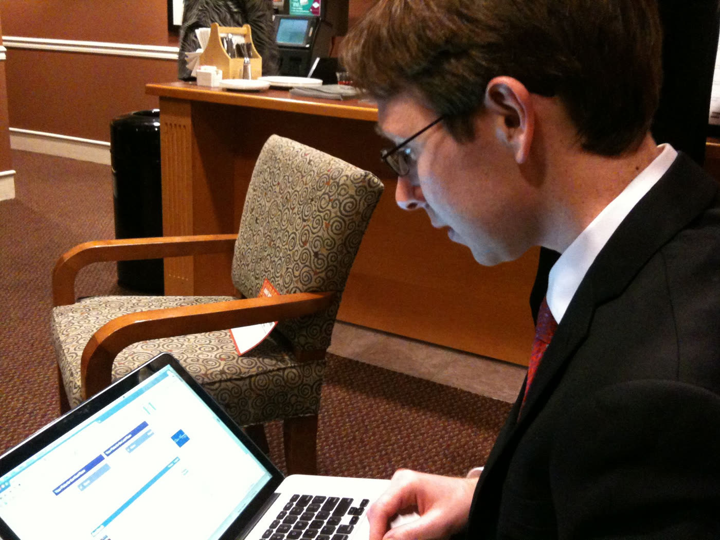 Robin in a suit at the track, working on a laptop