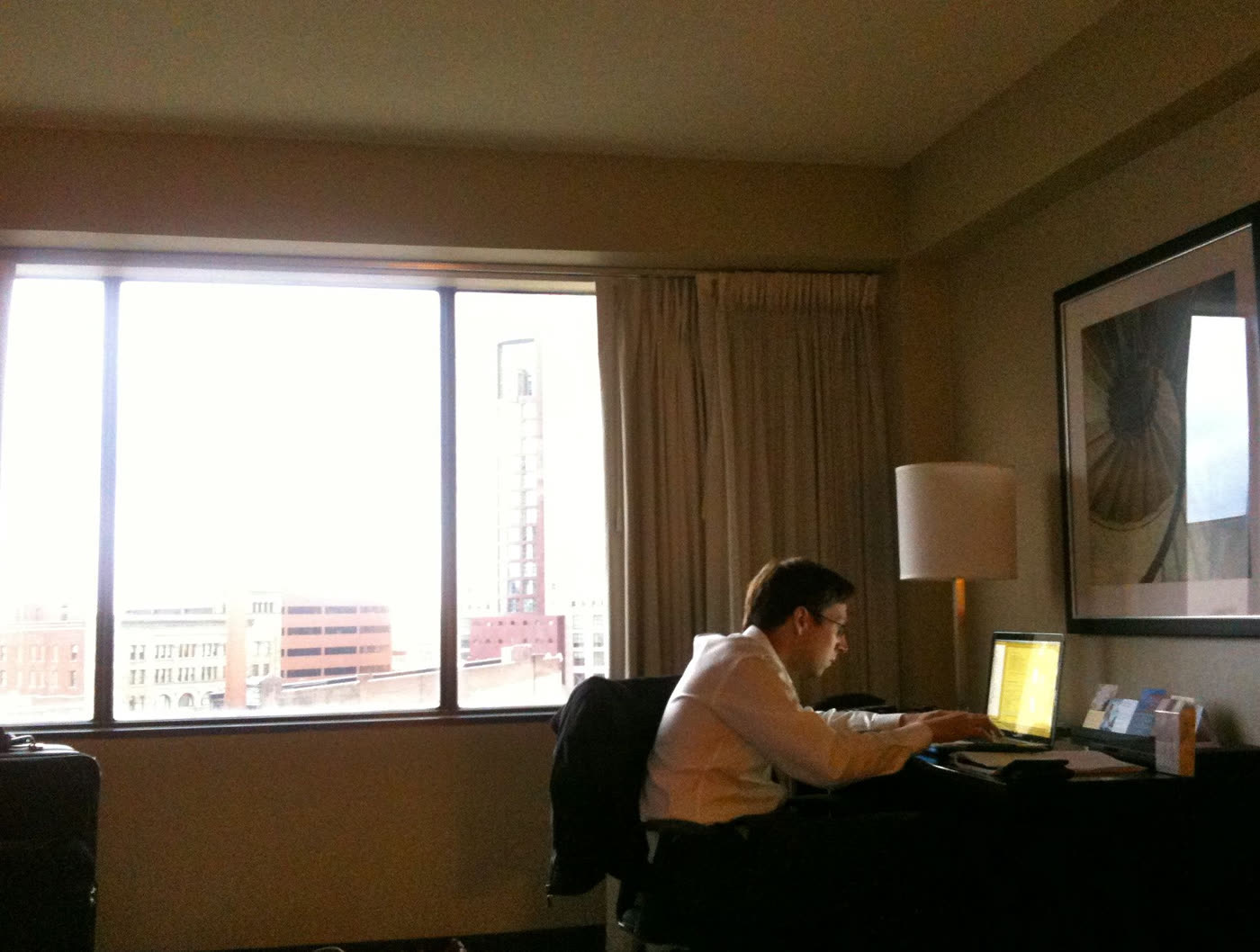 Robin at a hotel-room desk in Louisville, typing on a laptop by the window